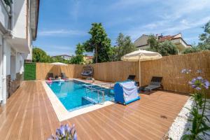 una piscina con sombrilla en una terraza de madera en Erva Apart Fethiye, en Fethiye