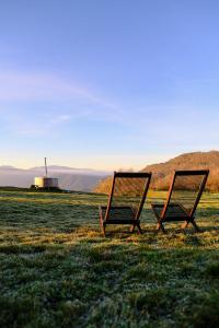 dos sillas sentadas en un campo con un molino de viento en el fondo en La casa de la masia, en Susqueda