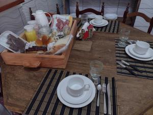 une table en bois avec des plaques blanches et une caisse de nourriture dans l'établissement Pousada Caminhos do Mel - Urubici - SC, à Urubici
