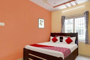 a bedroom with orange walls and a bed with red pillows at SEA COASTAL INN-3 in Kākināda