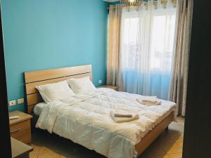 een slaapkamer met een groot bed met een blauwe muur bij Quiet & spacious city center apartment - 4 min walk in Tirana