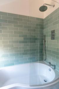 a bath tub in a bathroom with green tiles at King's Head Cottage in Hastings