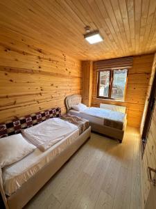 Dos camas en una habitación con paredes de madera. en EŞ Pansiyon, en Uzungöl