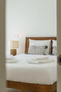 une chambre avec un lit avec des draps blancs et des oreillers dans l'établissement Villa Mauricio, à Mariquiteira