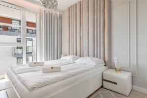 a white bedroom with a large white bed and a window at Marina Bay - Tre Mare Residence in Gdańsk
