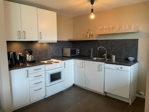 a kitchen with white cabinets and white appliances at Slinningen Apartment with free parking in Ålesund