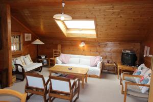 ein Wohnzimmer mit einem weißen Sofa und Holzwänden in der Unterkunft Arnica 2 in Chateau-d'Oex