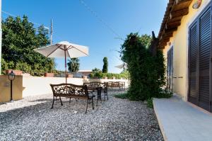 a patio with two chairs and an umbrella at Le Case Al Quadrato in Syracuse