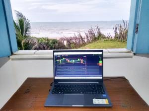 um computador portátil sentado numa mesa em frente a uma janela em Casinha Estrela do Mar o Oceano aos seus Pés em Aracati