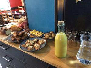 - une table avec des assiettes de nourriture et une bouteille de jus d'orange dans l'établissement Hôtel Bellevue Bagnoles Normandie, à Bagnoles-de-l'Orne