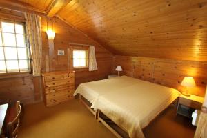 ein Schlafzimmer mit einem Bett in einer Holzhütte in der Unterkunft Arnica 2 in Chateau-d'Oex