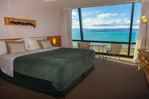 a bedroom with a large bed and a large window at Design Suites Calafate in El Calafate