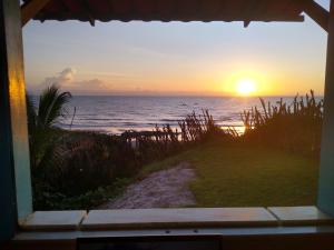 uma vista para o oceano a partir de uma janela ao pôr-do-sol em Casinha Estrela do Mar o Oceano aos seus Pés em Aracati