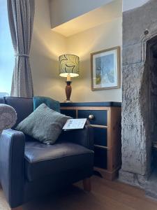 a living room with a blue couch and a lamp at Heart Of Hawes Holiday Cottage in Hawes