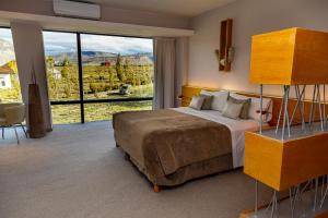 a bedroom with a bed and a large window at Design Suites Calafate in El Calafate