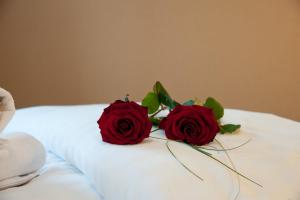two red roses sitting on top of a bed at Hotel Hofer in San Valentino alla Muta