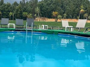 een zwembad met witte stoelen en blauw water bij Albergue e AL O Brasão Valença in Valença
