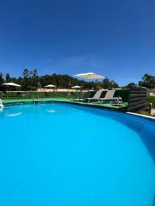 a large swimming pool with chairs and umbrellas at Albergue e AL O Brasão Valença in Valença