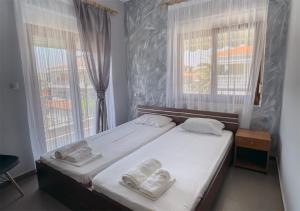 a bedroom with two beds and two windows at Niki Apartments in Paralia Dionysiou