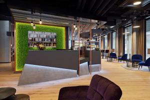a lobby with a bar with a green wall at Essential by Dorint Interlaken - New Opening in Interlaken