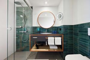 ein Bad mit einem Waschbecken und einem Spiegel in der Unterkunft Essential by Dorint Interlaken - New Opening in Interlaken