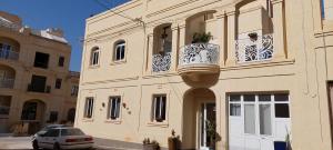 a building with a balcony and a car parked in front of it at Villa with private pool in Gozo in Munxar