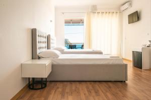 - une chambre blanche avec 2 lits et une fenêtre dans l'établissement Ionio Rooms, à Himarë