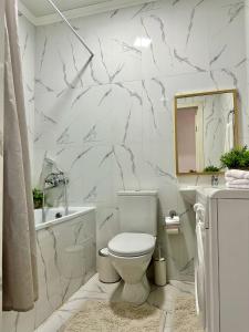 a white bathroom with a toilet and a tub and a sink at Студия ДЭНДИ с видом на горы in Almaty