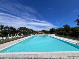 a large blue swimming pool with chairs and a blue sky at Casa Antia, nuovo bilocale con giardino in Residence con piscina in Numana