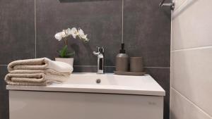 a bathroom sink with towels and flowers on it at Orchidea apartman in Balatonalmádi +8 photos
