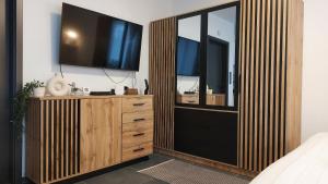 a bedroom with a tv and a dresser with a mirror at Orchidea apartman in Balatonalmádi