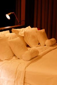 1 cama no hecha con sábanas y almohadas blancas en QS Marista Hotel, en Goiânia