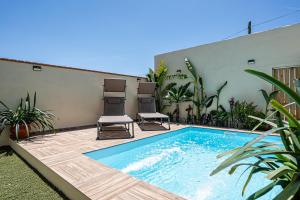a swimming pool with two chairs next to a building at Casa Dorca 1 in Conil de la Frontera