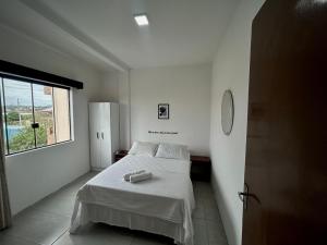 a white bedroom with a bed and a window at Hotel & Pousada Bella Vista in Florianópolis