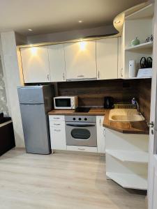 a kitchen with white cabinets and a sink and a refrigerator at Lux Apartment Sisi in Burgas