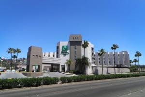 a large building with palm trees in front of a street at Holiday Inn Tijuana Zona Rio, an IHG Hotel in Tijuana