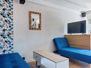 uma sala de estar com um sofá azul e uma televisão em Escapade marine a carnac Maison 4 personnes toute équipée, au calme entre plage et ville em Carnac
