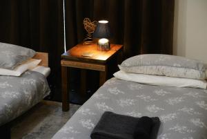 a bedroom with two beds and a table with a lamp at Hillfields Farm Barn - A Rural Equestrian Escape in Coventry