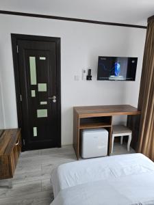 a bedroom with a bed and a desk and a tv at Pensiunea Minerva in Bistriţa