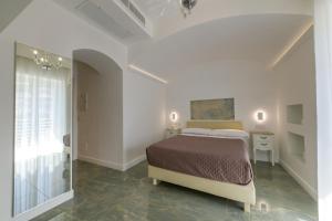 アグローポリにあるDonna Adriana Roomsの白いベッドルーム(ベッド1台、鏡付)