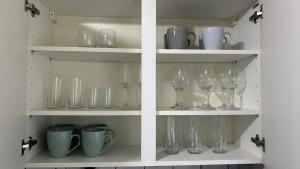 two shelves with wine glasses and cups on them at DK House in Colchester