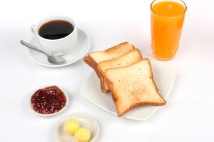 a white table with a plate of toast and a cup of coffee at Paris Senlis Hostel Plus in Chimbote
