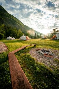 a group of tents in a field with a fire pit at Glamping Gozdna Jasa in Bovec