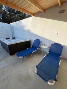 Duas cadeiras azuis e uma cama num pátio em Mano's House em Triopetra