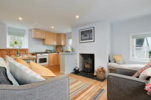 een woonkamer met twee banken en een keuken bij Corner Cottage in Penzance