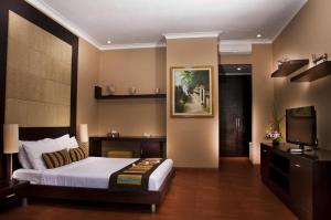 a bedroom with a bed and a flat screen tv at Sindhu Mertha Suite in Sanur