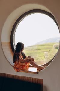 une femme assise sur un rebord de fenêtre devant un miroir dans l'établissement M.A.K.home, à Vyshka