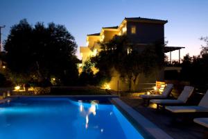 a swimming pool in front of a house at night at Maistros Apartments in Tsoukalades