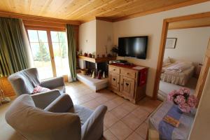 a living room with a tv and a couch and chairs at Forêt C2 in Chateau-d'Oex