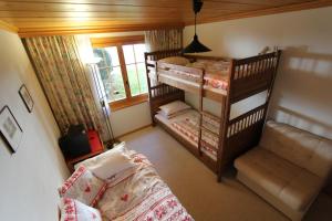 a bedroom with two bunk beds and a couch at Forêt C2 in Chateau-d'Oex